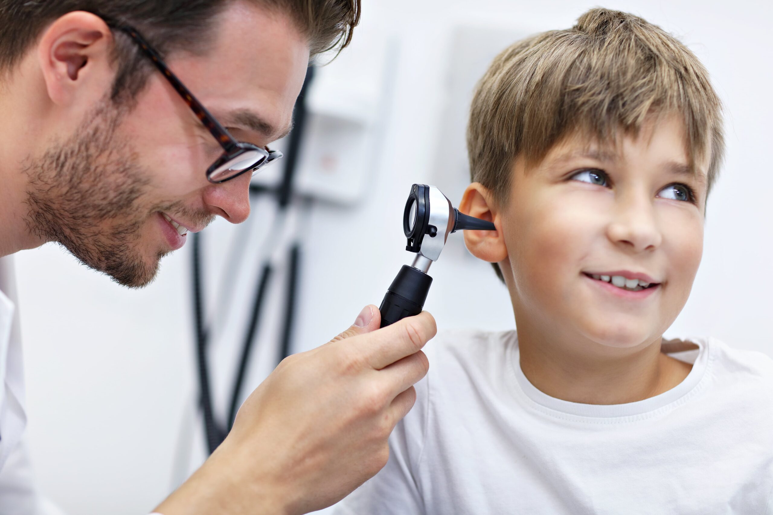 Doctor examining a young boy's ear with an otoscope