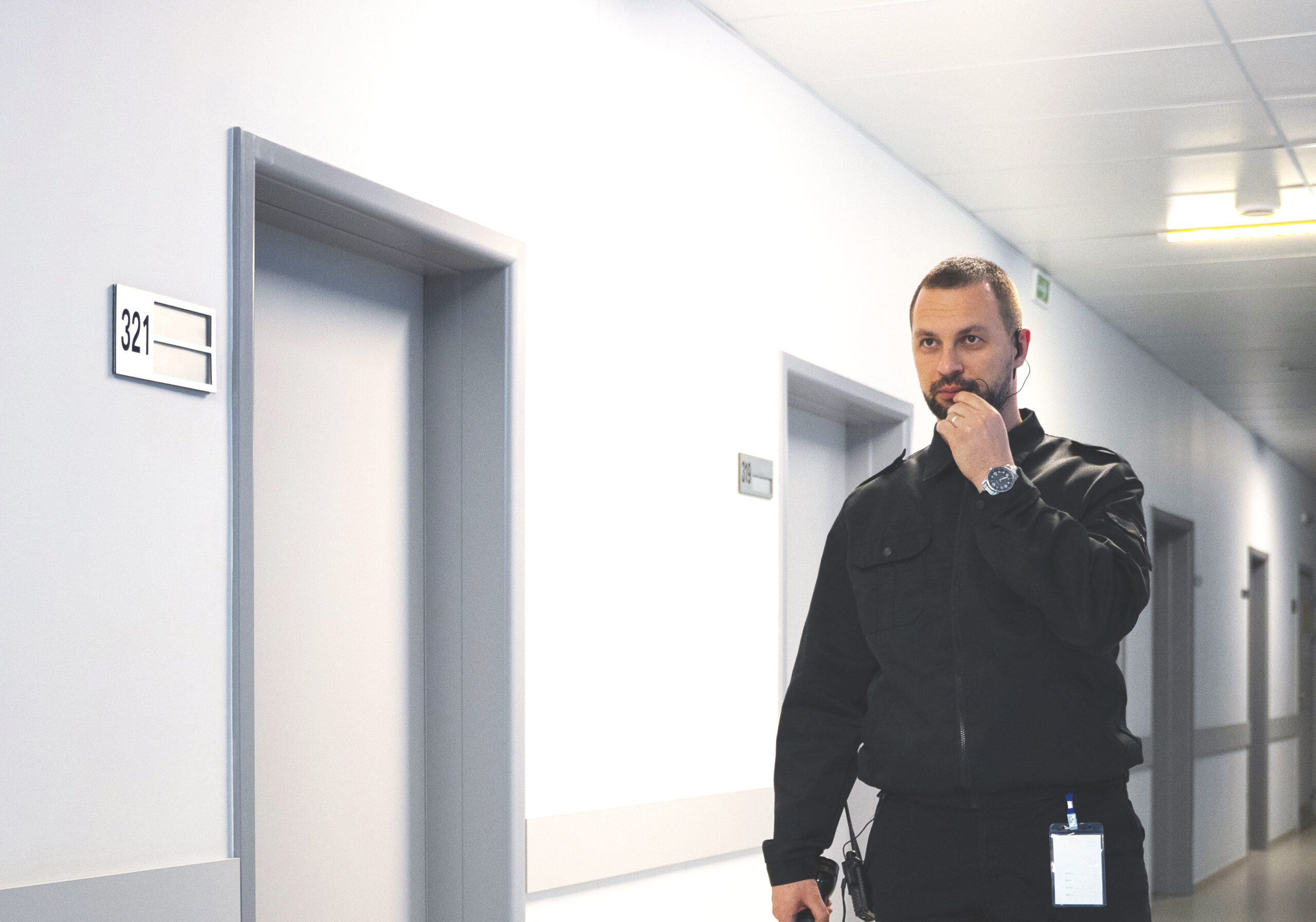 Security guard walking down a hallway while speaking into a handheld radio